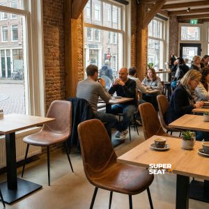 Super-Seat | Charlie vintage leather bucket chairs cognac Des chaises en cuir de couleur cognac, des tables en bois, de grandes fenêtres et des plantes créent une atmosphère chaleureuse. | Mobilier de restauration