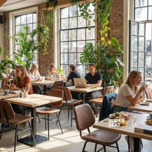 Super-Seat | Houten tafels, zwarte metalen onderstellen, groene planten, stoelen en barkrukken in café. | Horecameubilair