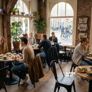 Super-Seat | Chaises Lix vintage mat Black wood | Chaises et tables Lix en bois noir, sol en bois noir, ambiance café lumineuse avec de grandes fenêtres. | Mobilier de restauration