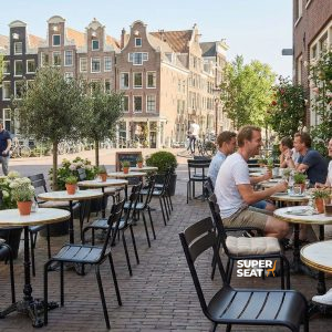 Super-Seat | Chaises et tables empilables en métal noir sur une terrasse en clinker avec des plantes et une vue sur la ville. | Mobilier de restauration