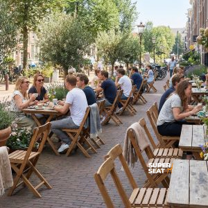 Super-Seat | Tables en bois brun, chaises de patio en bois vintage dans la rue, soleil et fleurs. | Mobilier de restauration