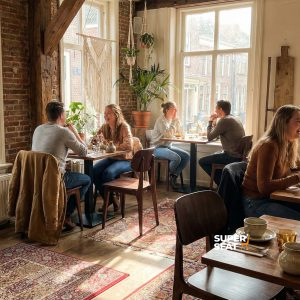 Super-Seat | Bonn Café Stoelen en Tafels Bruine Scandinavische stoelen en houten tafels, bakstenen muren, planten en warme tapijten. | Horecameubilair