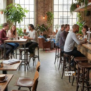 Super-Seat | Houten stoelen, zwarte bistro tafels, houten bar met krukken in licht café met planten en ramen. | Horecameubilair