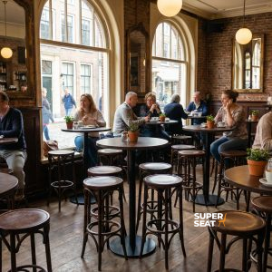 Super-Seat | Tables de bar rondes noires, chaises en bois, grandes fenêtres, plantes, ambiance chaleureuse dans le café. | Mobilier de restauration