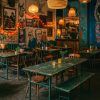 Super-Seat | Un café confortable avec des tables et des chaises en bois dépareillées | Houten stoelen en tafels, groene bladen, vintage armée vouwtafels, bloemvaasjes, metalen accenten. | Horecameubilair