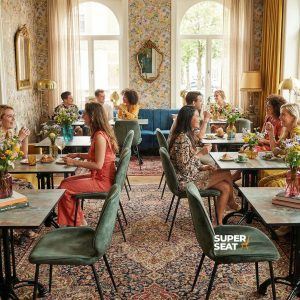Super-Seat |Groupes autour de tables en HPL cuivre rouillé, de banquettes bleues, de papier peint floral et de grandes fenêtres dans un café élégant. | Mobilier de restauration