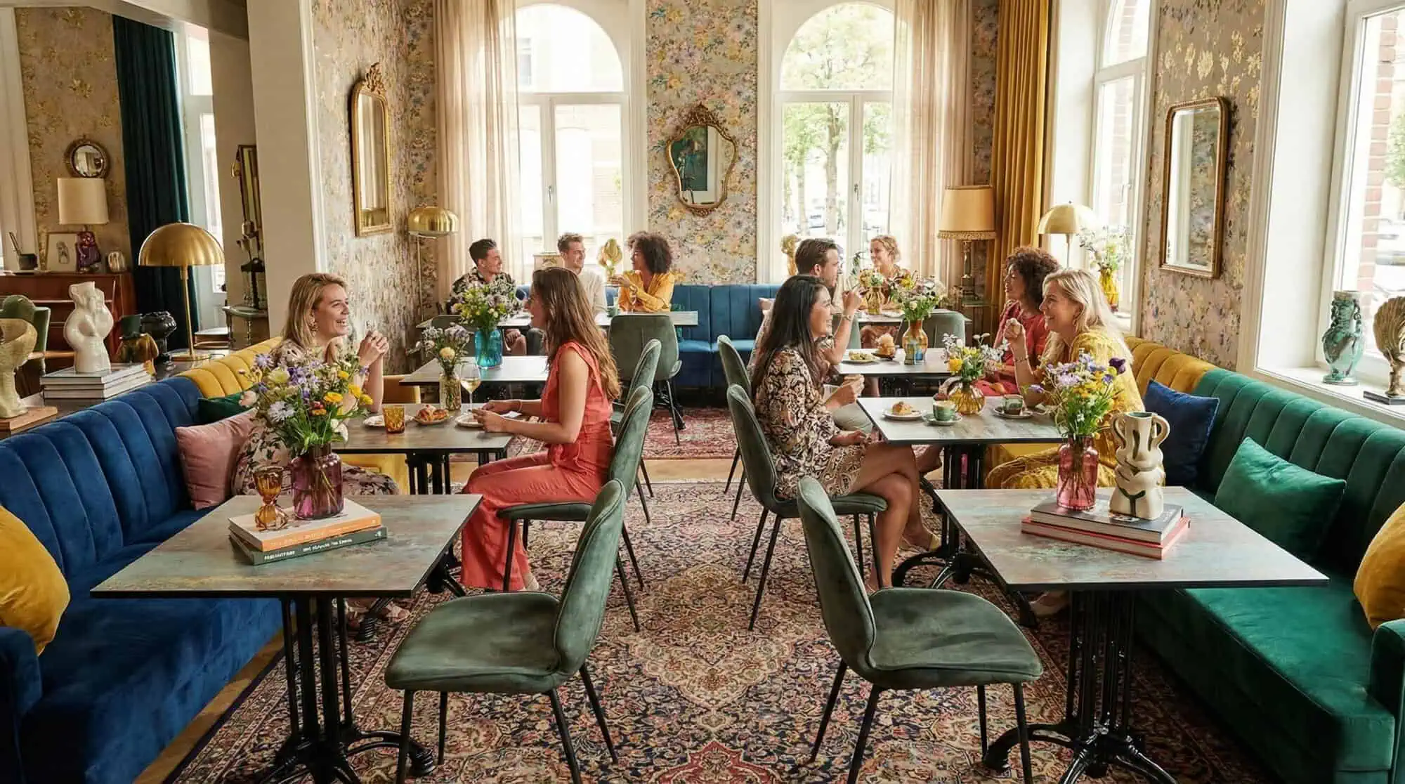 Super-Seat |Groupes autour de tables en HPL cuivre rouillé, de banquettes bleues, de papier peint floral et de grandes fenêtres dans un café élégant. | Mobilier de restauration
