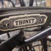 Super-Seat | Gros plan sur la structure d'une chaise en métal noir portant l'étiquette "THONET" | Structure en métal noir, formes gracieuses, pieds entrelacés ; style Thonet vintage. | Mobilier de restauration