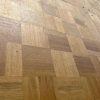 Super-Seat | Gros plan sur une piste de danse mobile usée | Parquet en bois usé en forme d'échiquier avec des rayures visibles, bord en laiton visible |. | Mobilier de restauration