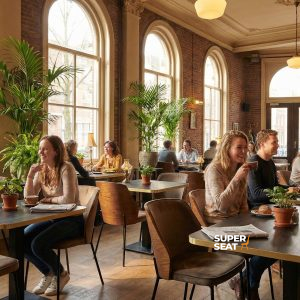 Super-Seat | New York chaises design en bois velours Mocha | Chaises en velours brun moka, tables et tabourets en bois dans un espace café ouvert et lumineux avec des plantes. | Mobilier de restauration