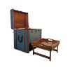 Super-Seat | Table d'appoint valise bleue avec sangles en cuir marron, détails métalliques, à côté d'une table plateau blanche. | Mobilier pour la restauration