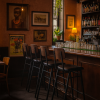 Super-Seat | Un bar peu éclairé avec quatre Tabourets de bar design Jody pour la restauration noir/brun empilables | Zwarte en bruine stapelbare barkrukken van hout en metaal, houten bar, glazen flessen op planken. | Horecameubilair