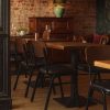 Super-Seat | A restaurant dining area with wooden tables and Chaises design Jody pour la restauration noir / brun empilables | Houten tafels en zwarte/bruine stapelbare stoelen van metaal en kunststof, warme sfeerverlichting. | Horecameubilair