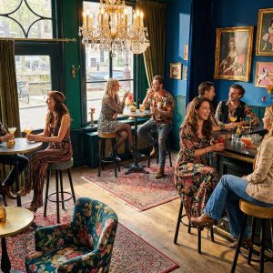 Super-Seat | Tabourets de bar en velours noir et ocre, tables en bois, chaises en métal dans un café coloré. | Mobilier de restauration