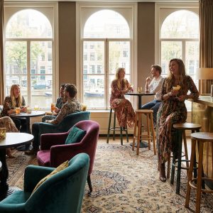 Super-Seat | Bar Interior Inspiration | Chaises en velours, tabourets de bar en laiton et tables près de grandes fenêtres avec des accents dorés et des étagères en bois. | Mobilier de restauration