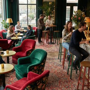 Chaises florales, tables rondes en bois, bar en marbre, tabourets de bar en cuir, grandes fenêtres. | Mobilier de restauration