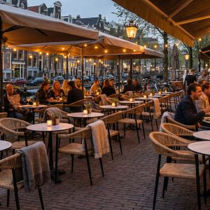 Super-Seat | Waterfront Restaurant Tables en bois, chaises grises et noires, tabourets de bar en bois sur une terrasse en pierre sous de grands parasols blancs. | Mobilier de restauration